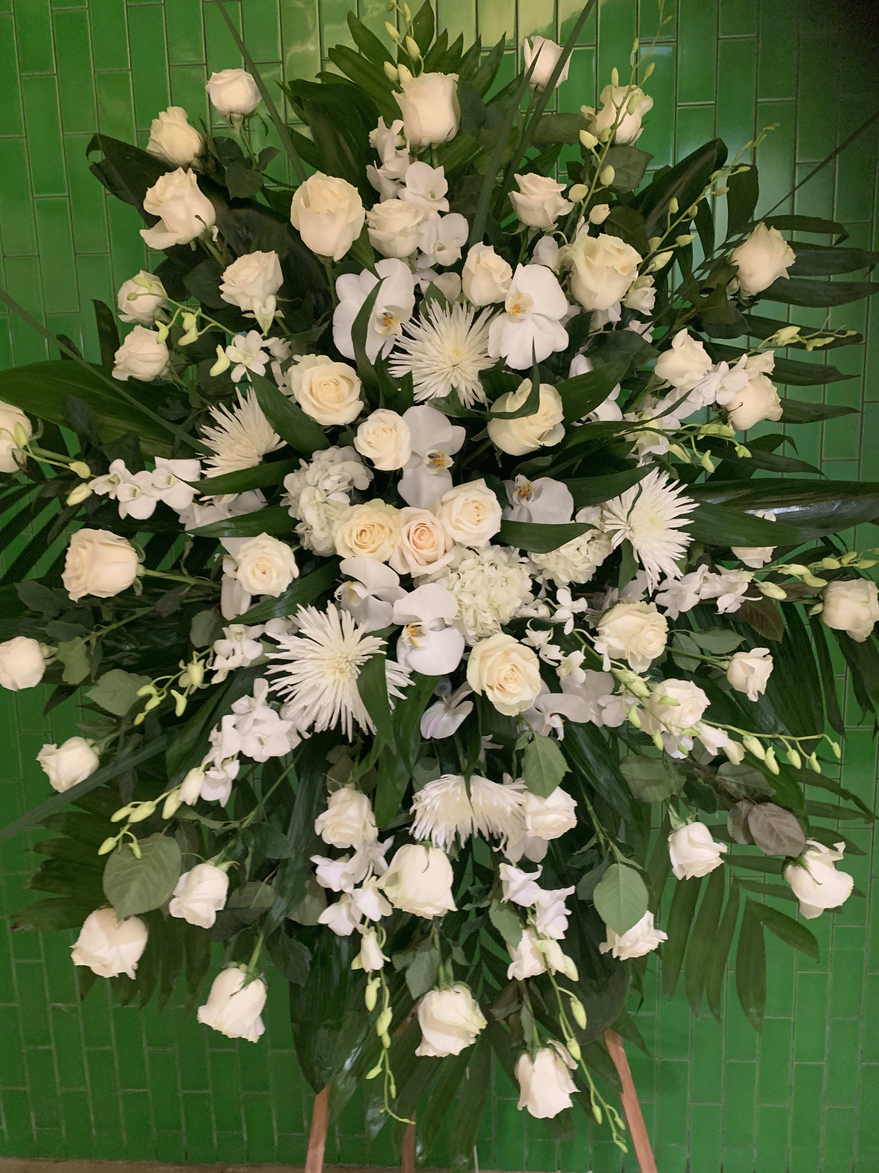 Large white floral spray with roses and orchids against green tiles