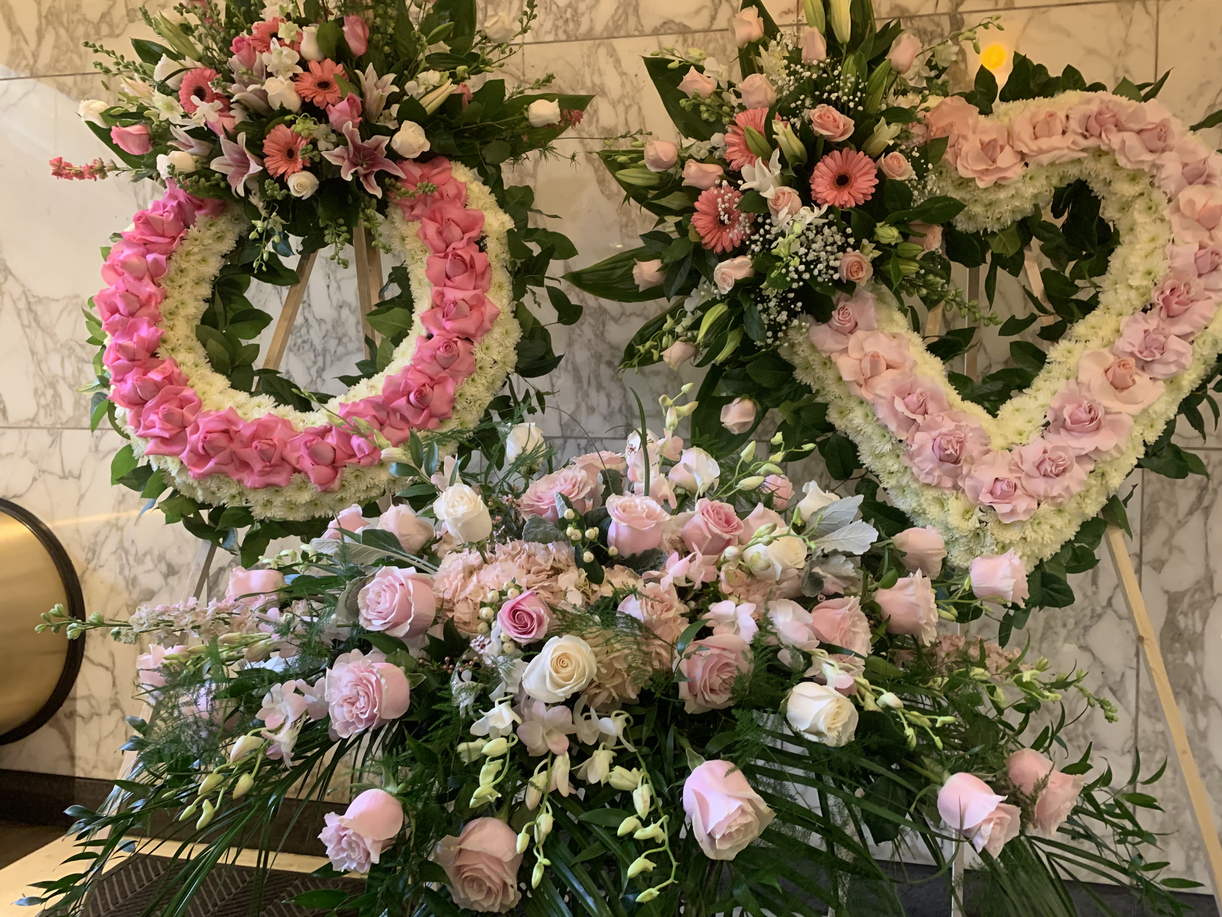 Pink and white floral wreaths and bouquets arranged on stands