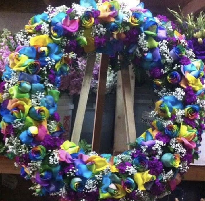 Large rainbow floral wreath with multicolored roses and white filler flowers