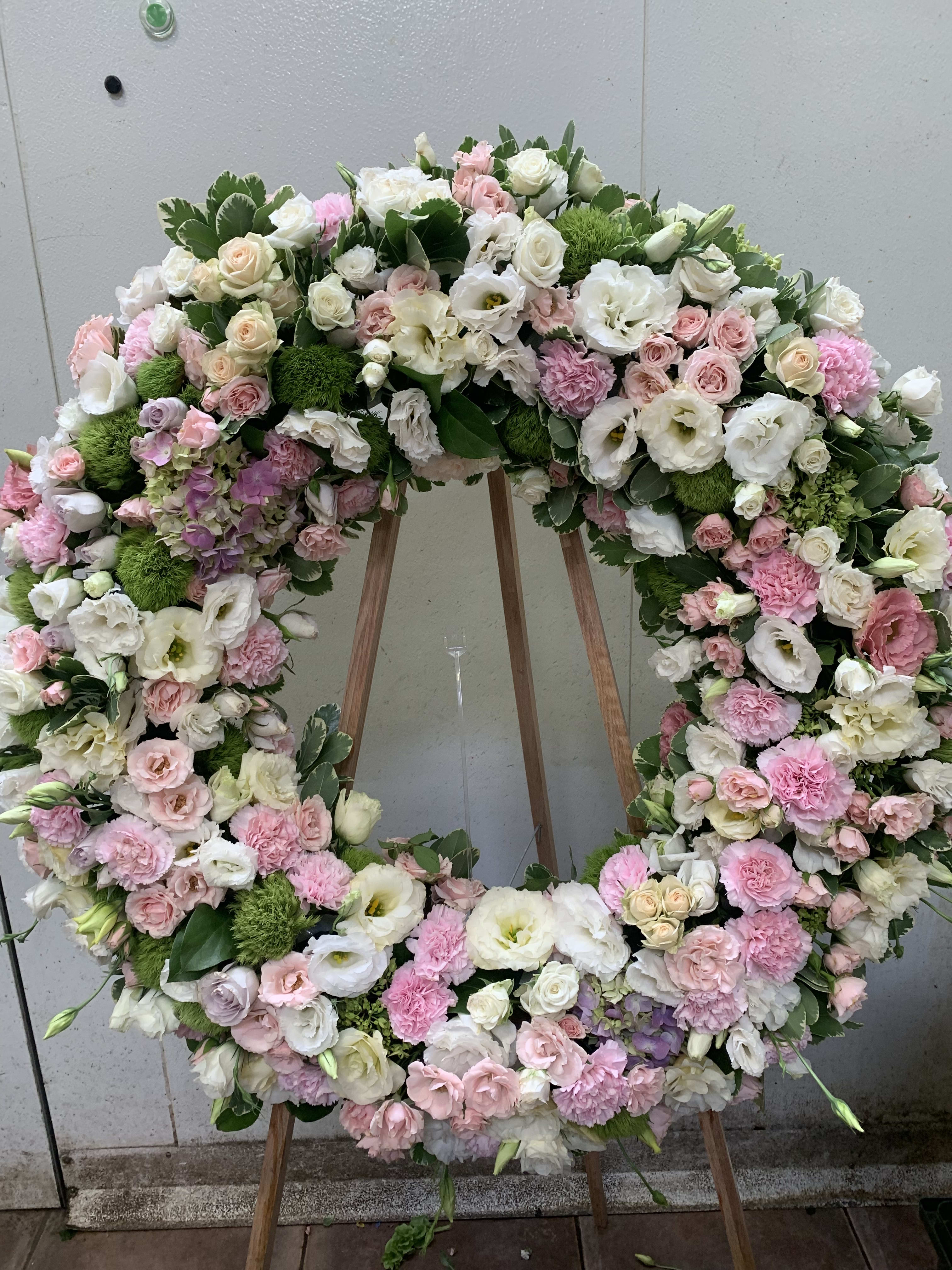 Large pastel floral wreath on an easel with pink and white blooms