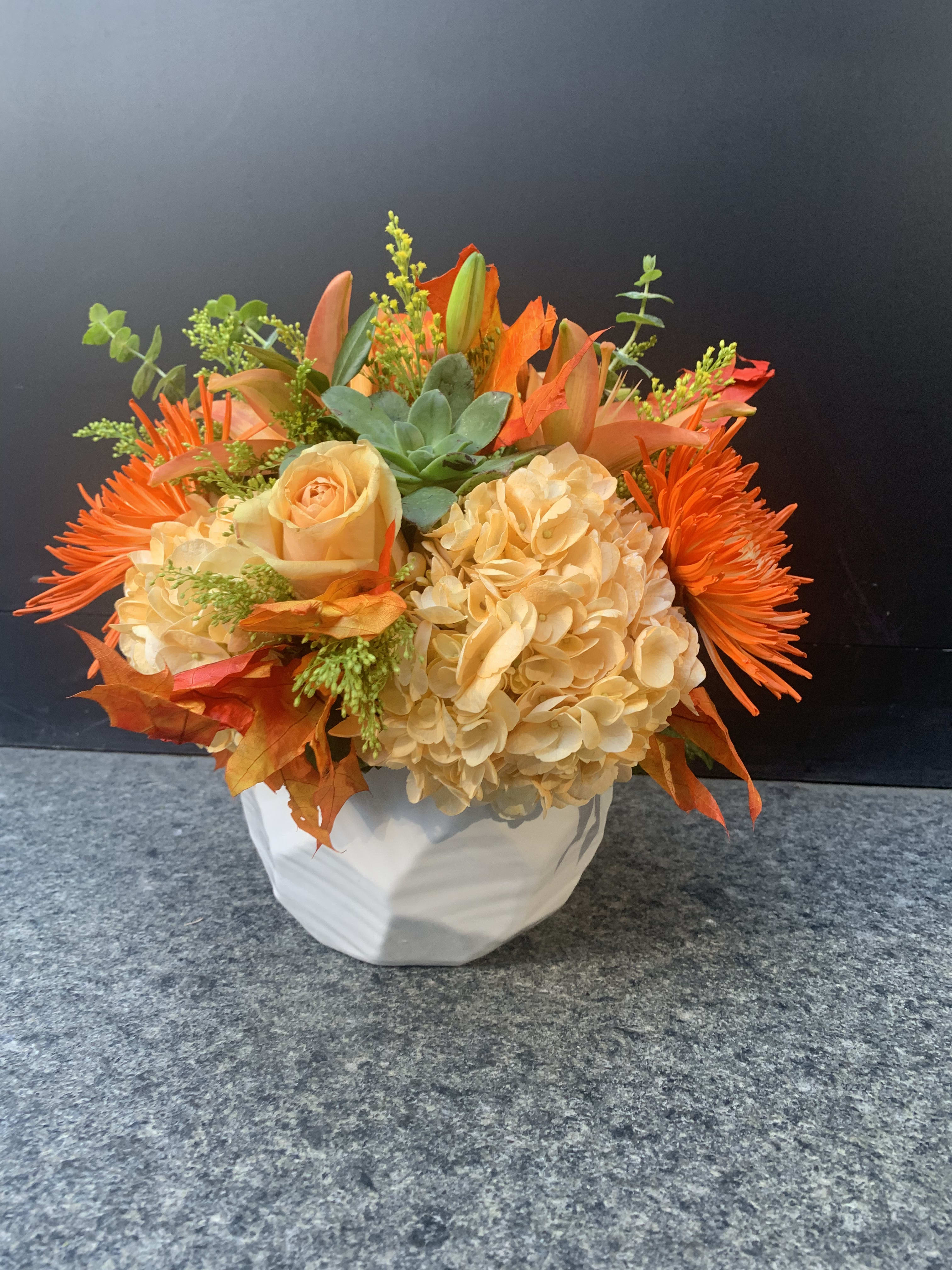 Orange and cream floral arrangement in a white vase