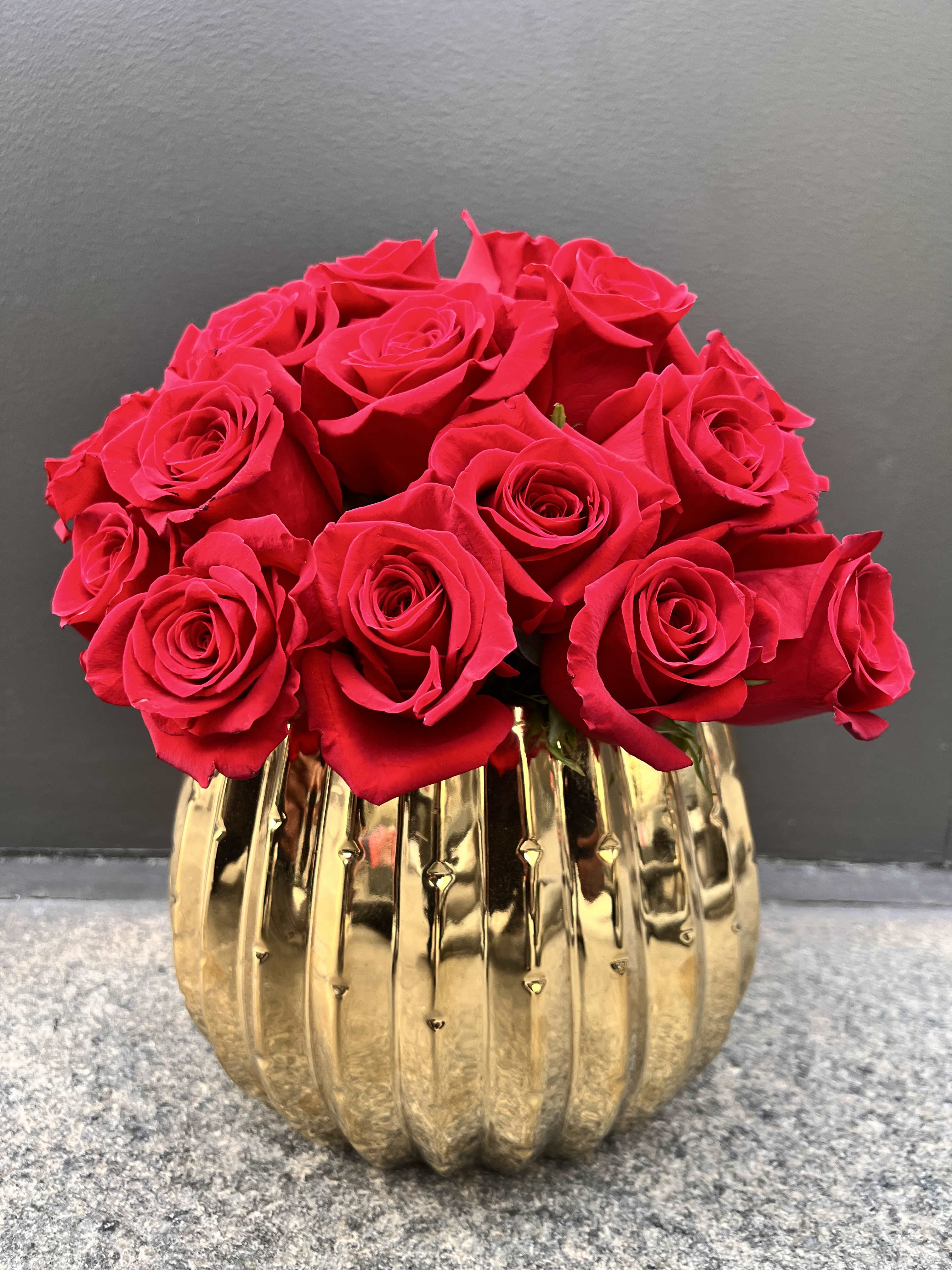 Red roses arranged in a gold ribbed vase