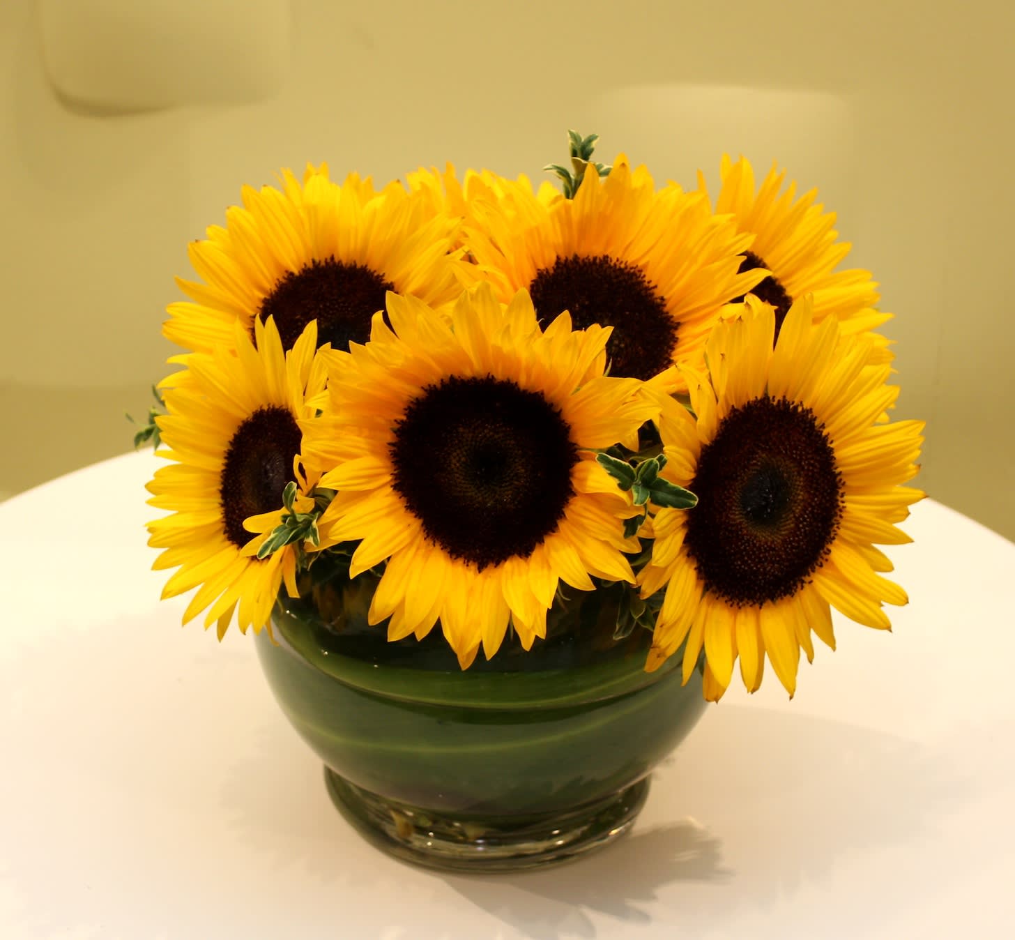Bouquet of sunflowers in a green glass bowl vase