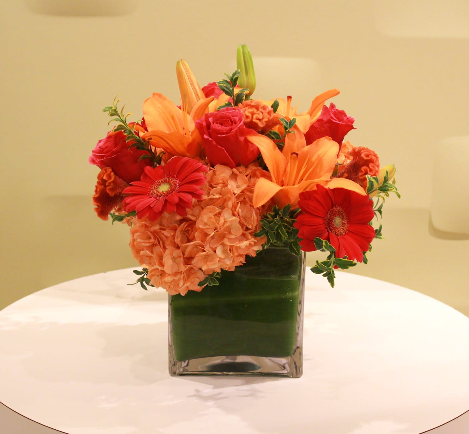 ENCHANTED RED  - Just Peachy comes in an elegant square container featuring Hydrangea's, Seasonal Gerber Daises, Lilies, and Roses with Green Accents  