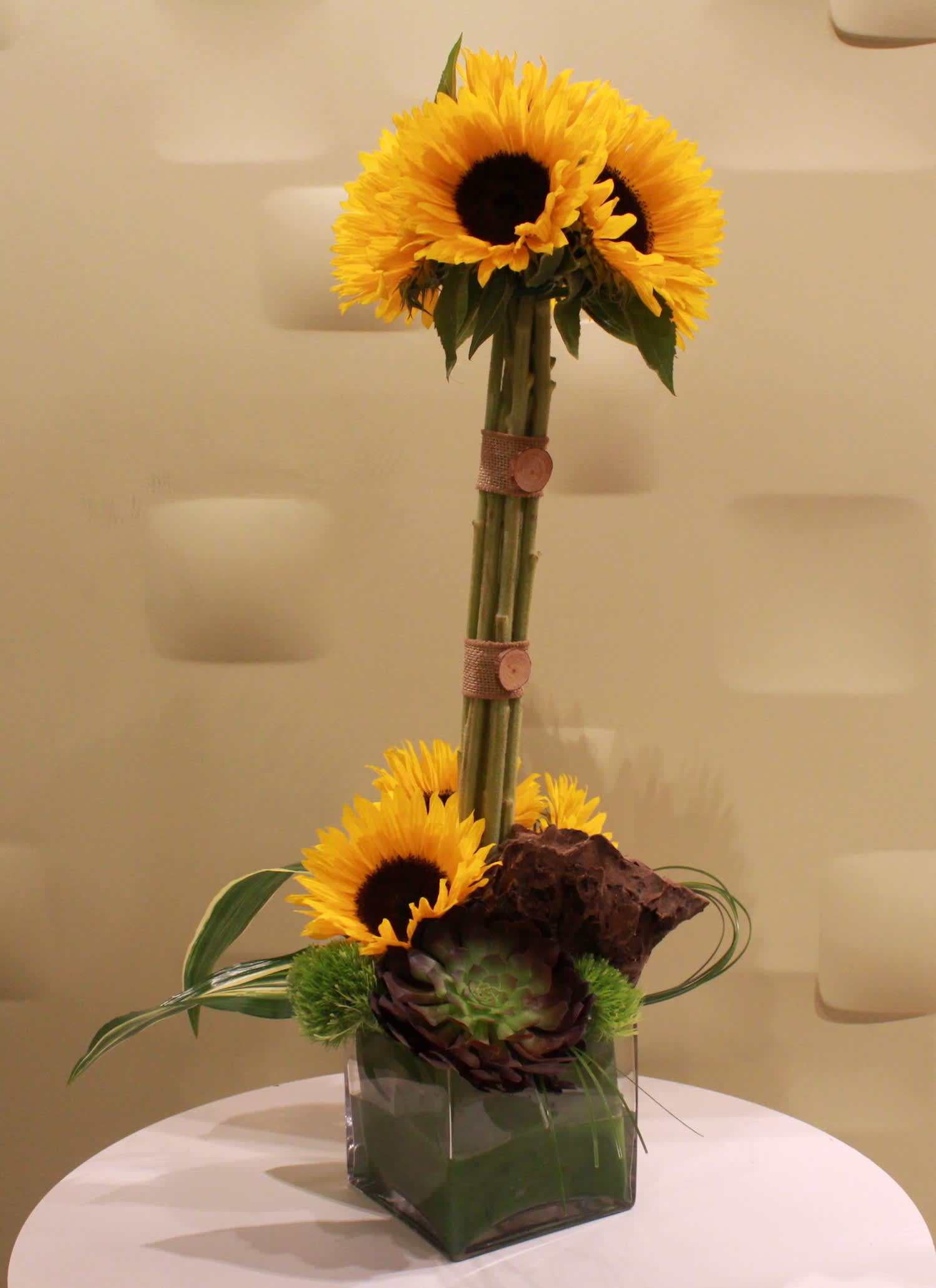 Sunflower arrangement in a square glass vase with decorative accents