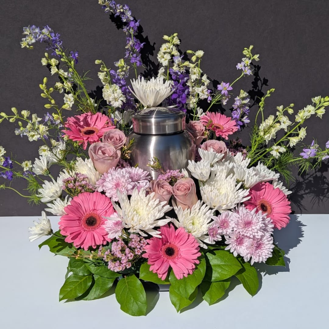 Pink and white flowers arranged around a stainless steel urn