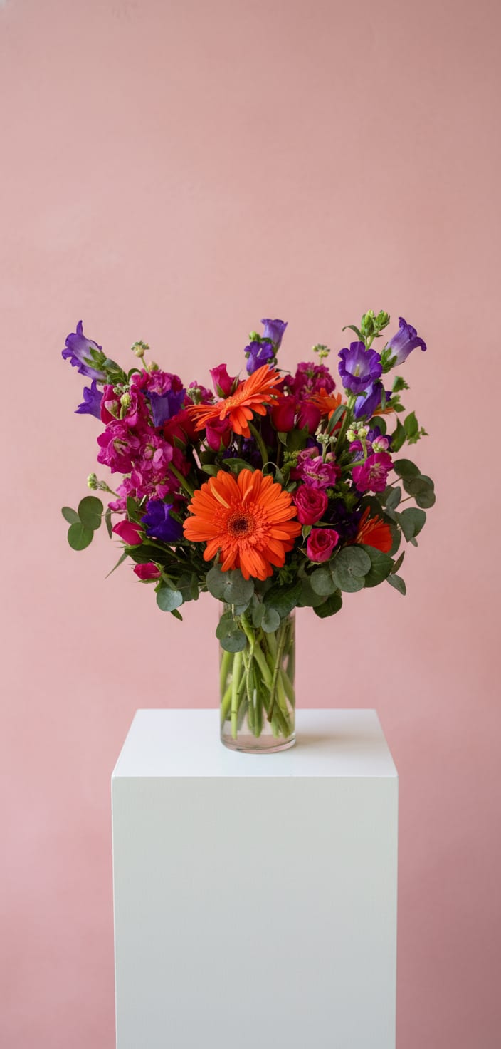 Bright mixed bouquet in a clear glass vase with orange and purple flowers
