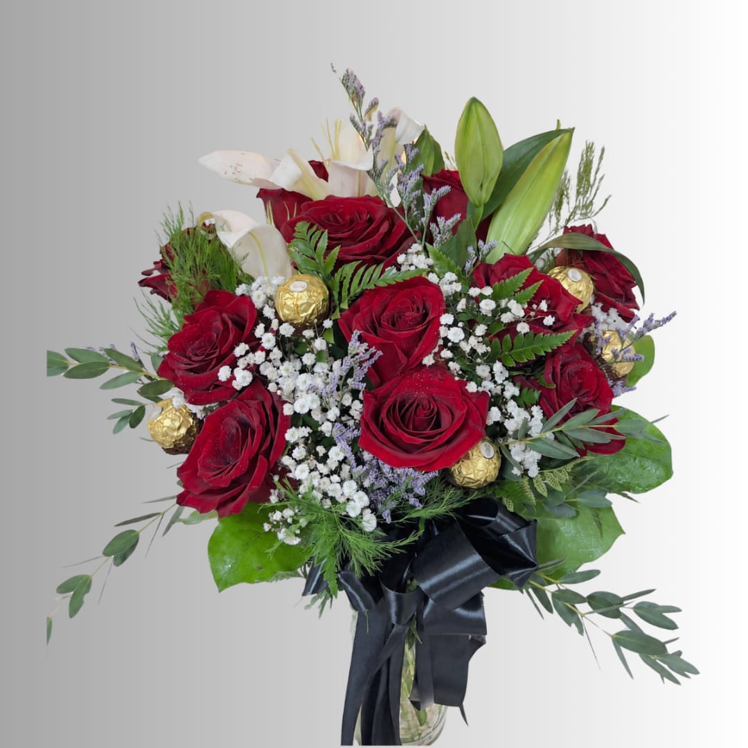 Bouquet of red roses, white lilies, and gold chocolates in a glass vase