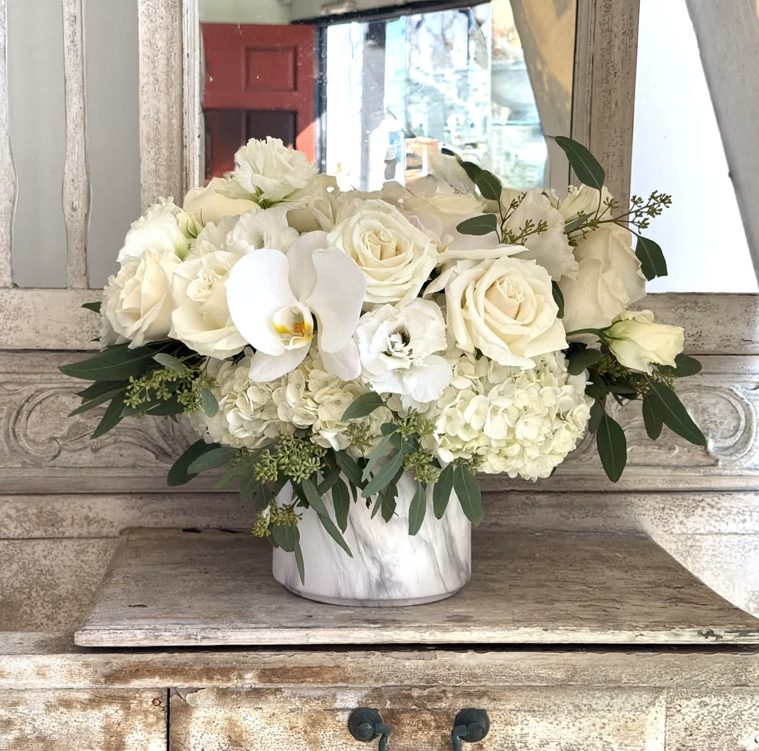 White roses and orchids arranged in a marble vase