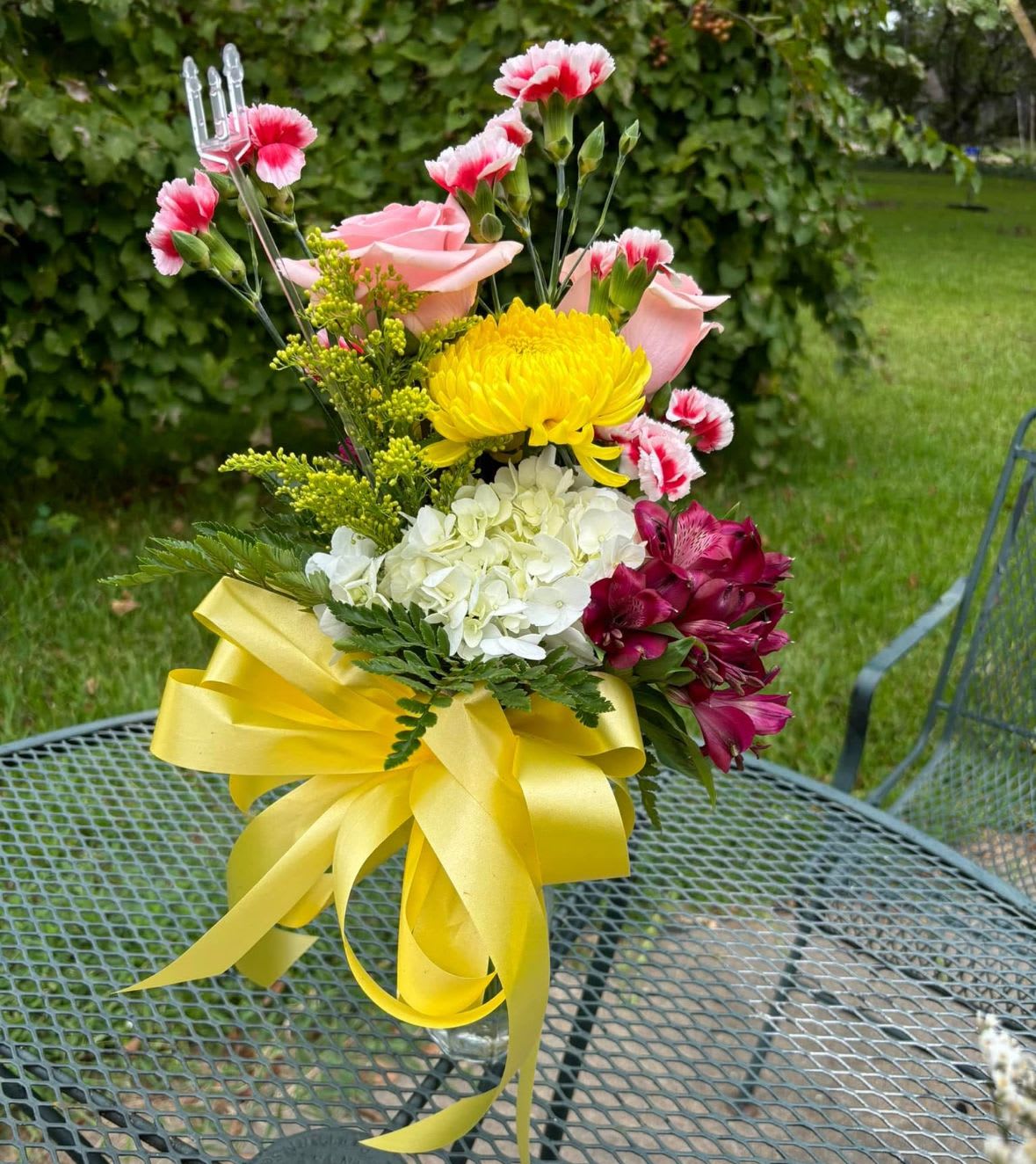 Bouquet of pink roses, yellow chrysanthemum, white hydrangea, and magenta alstroemeria in a glass vase