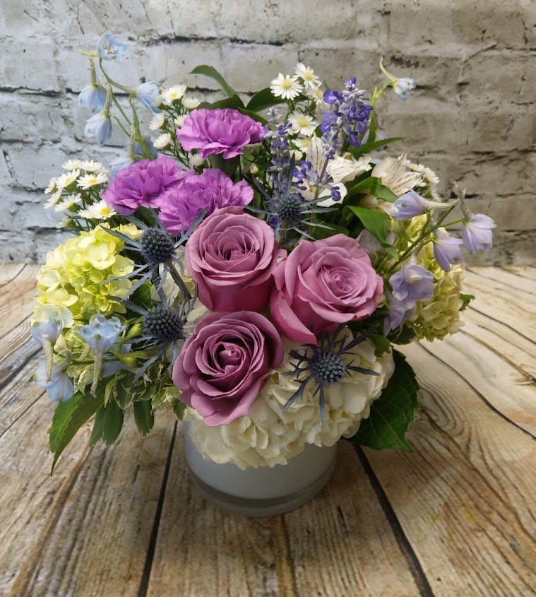 Pink roses and purple flowers arranged in a white vase