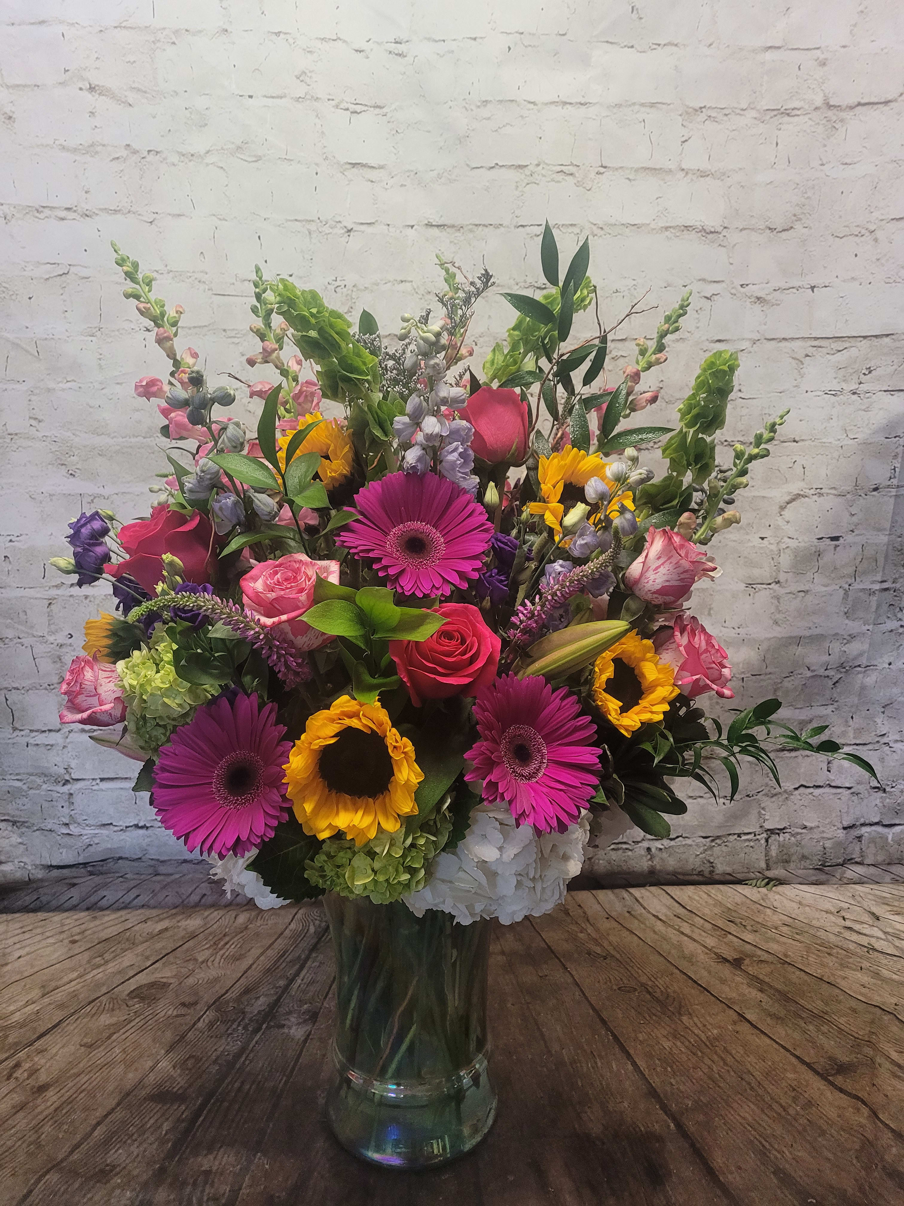 Mixed bouquet in a clear glass vase with pink, yellow, and purple blooms