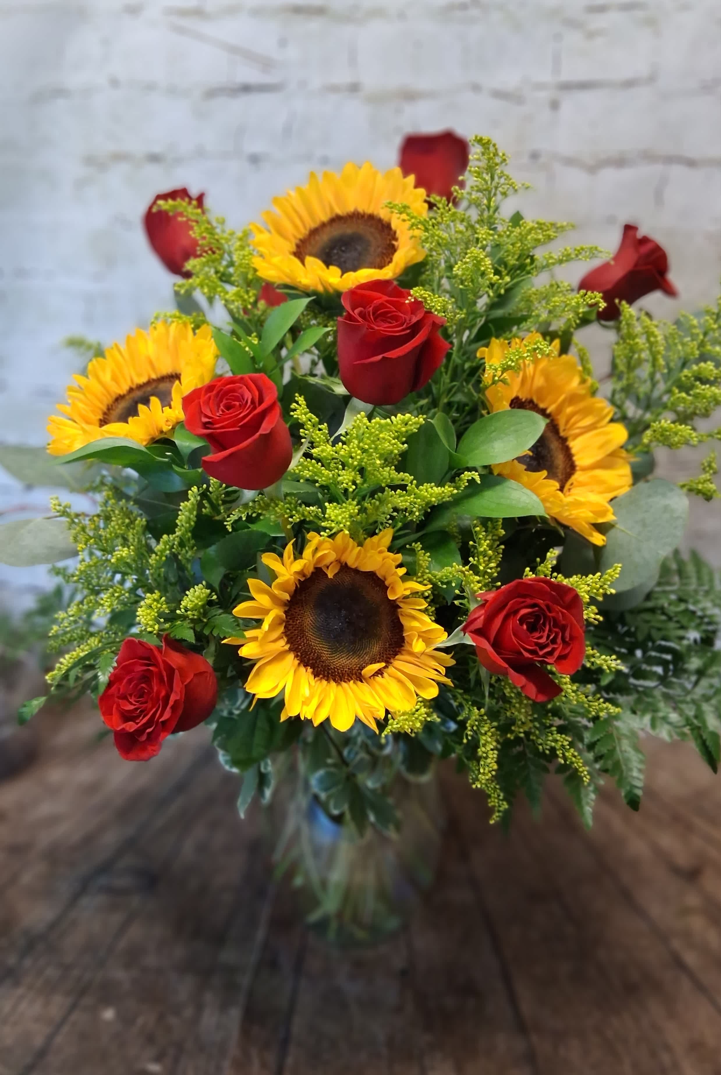 Bouquet of red roses and yellow sunflowers in a glass vase