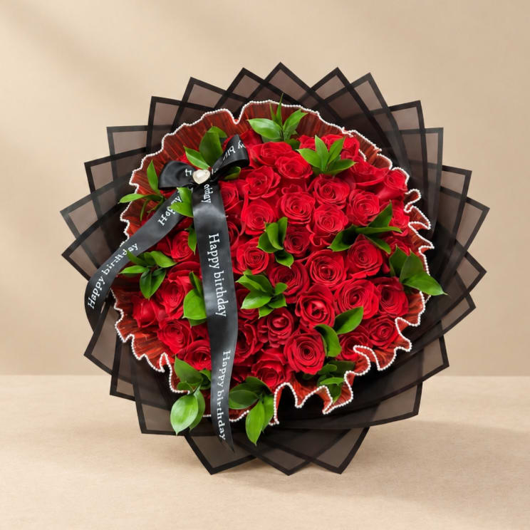 Bouquet of red roses with green accents and a black birthday ribbon