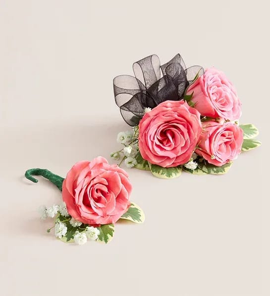 Pink Spray Rose Corsage and Boutonniere (Black) - NEW Make a special occasion even more memorable with our hand-designed corsage and boutonniere pairing. Each is made with carefully chosen pink spray roses complemented with baby’s-breath and greenery. The corsage, which can be worn on the wrist or pinned to clothing, comes with ribbon in your choice of seven colors: black, gold, light blue, light pink, purple, silver, or white.