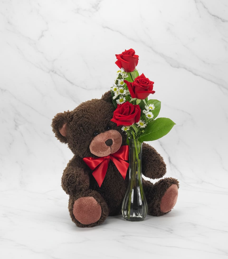 Teddy bear beside a small vase of red roses and white daisies