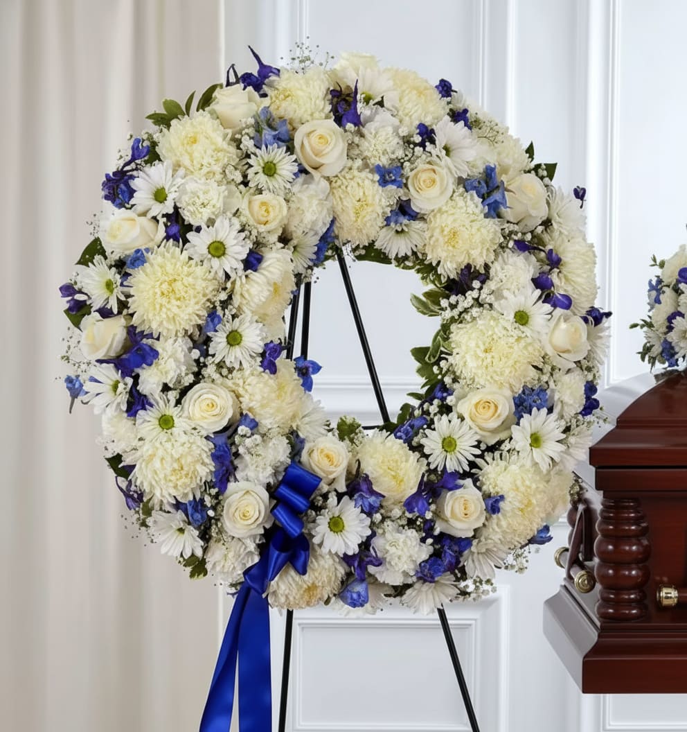 White and blue floral wreath on a stand with a blue ribbon