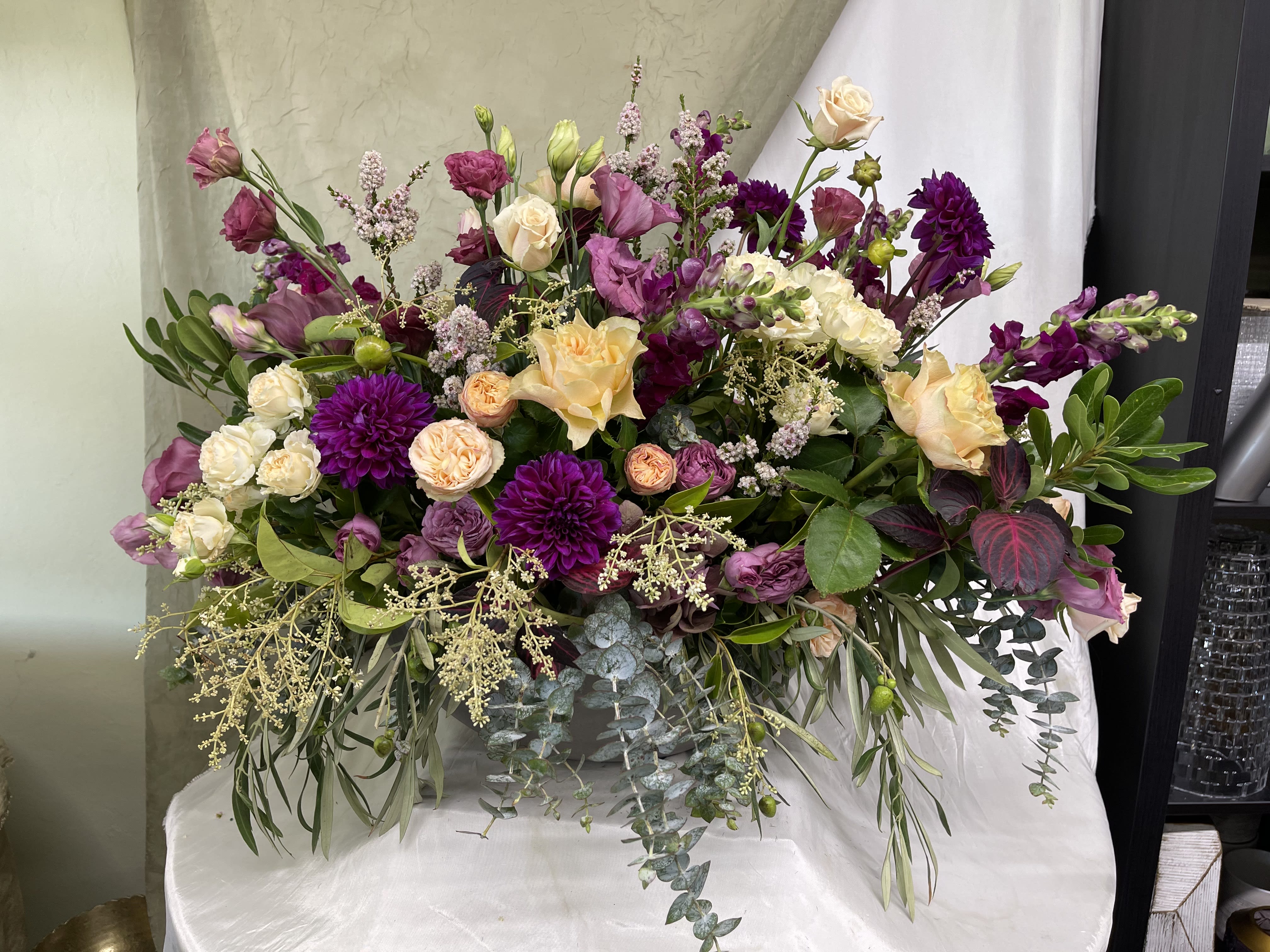 Large bouquet of purple, pink, and cream flowers with trailing greenery