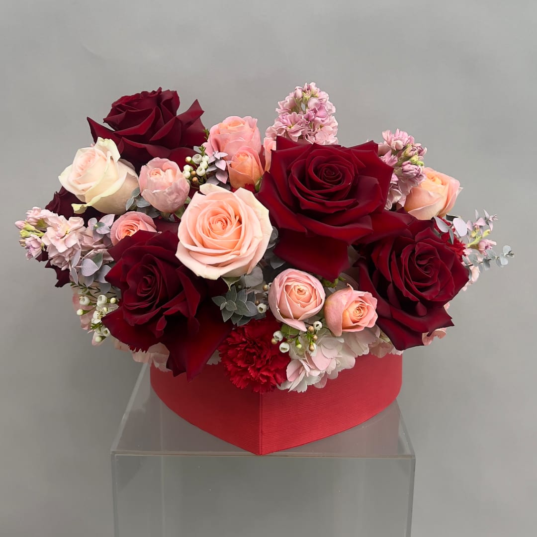 Heart-shaped box arrangement of red and blush roses with pink flowers