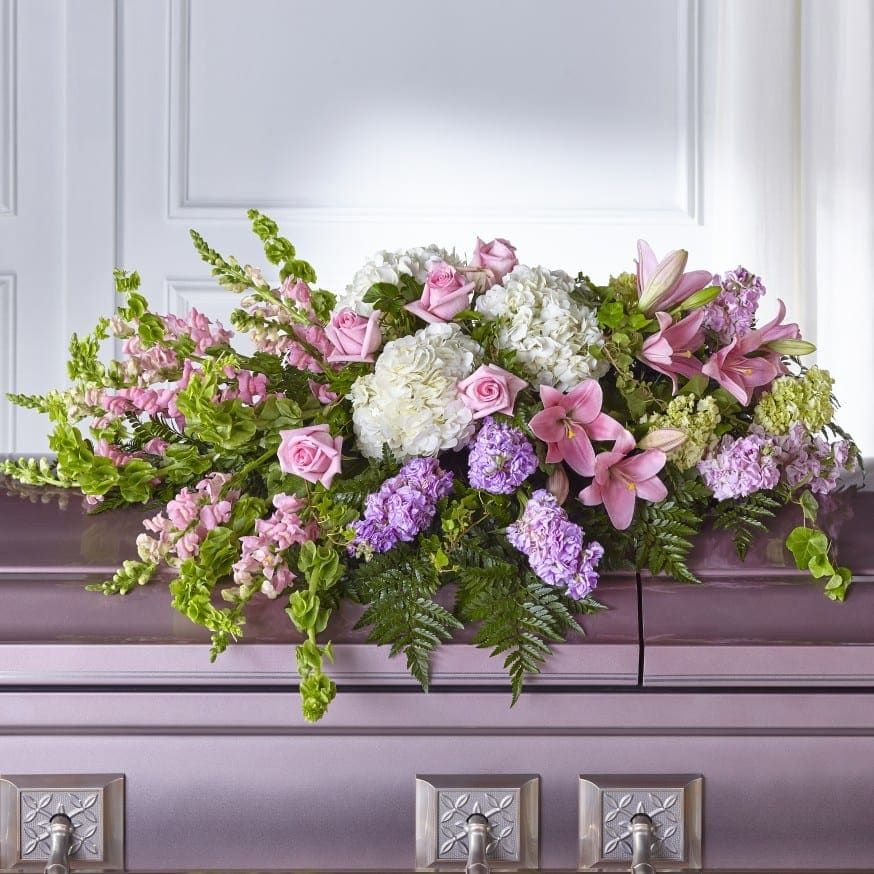 Pink and white floral casket spray with lilies and roses
