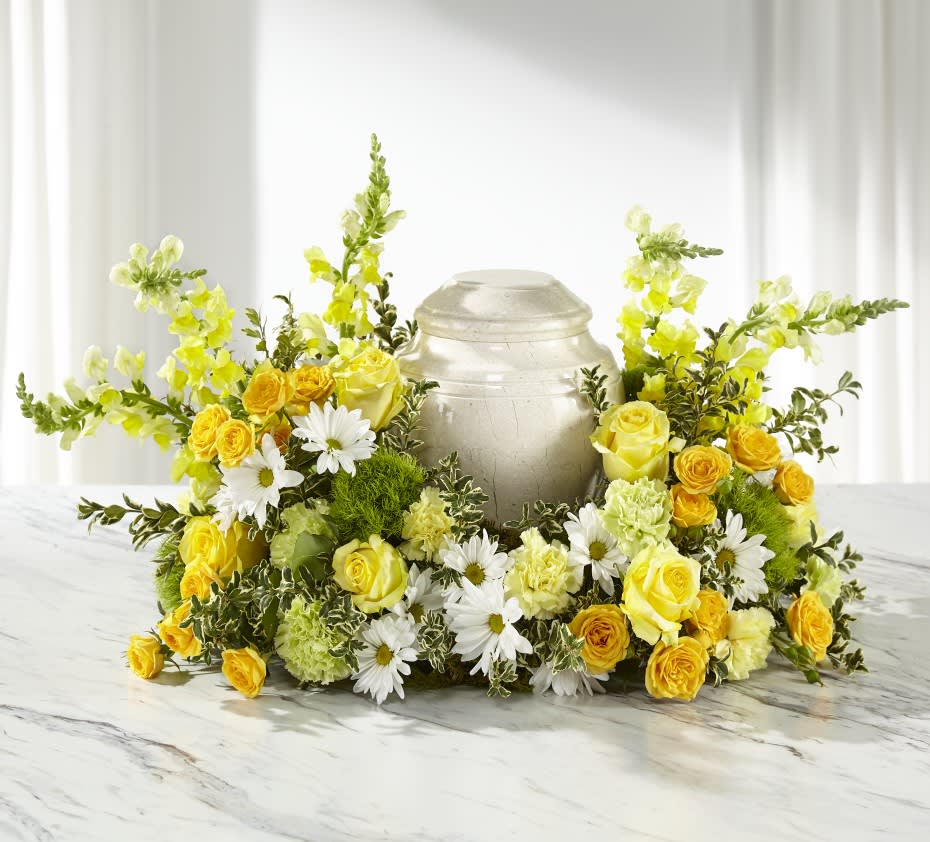 Yellow roses and white daisies arranged around a silver urn