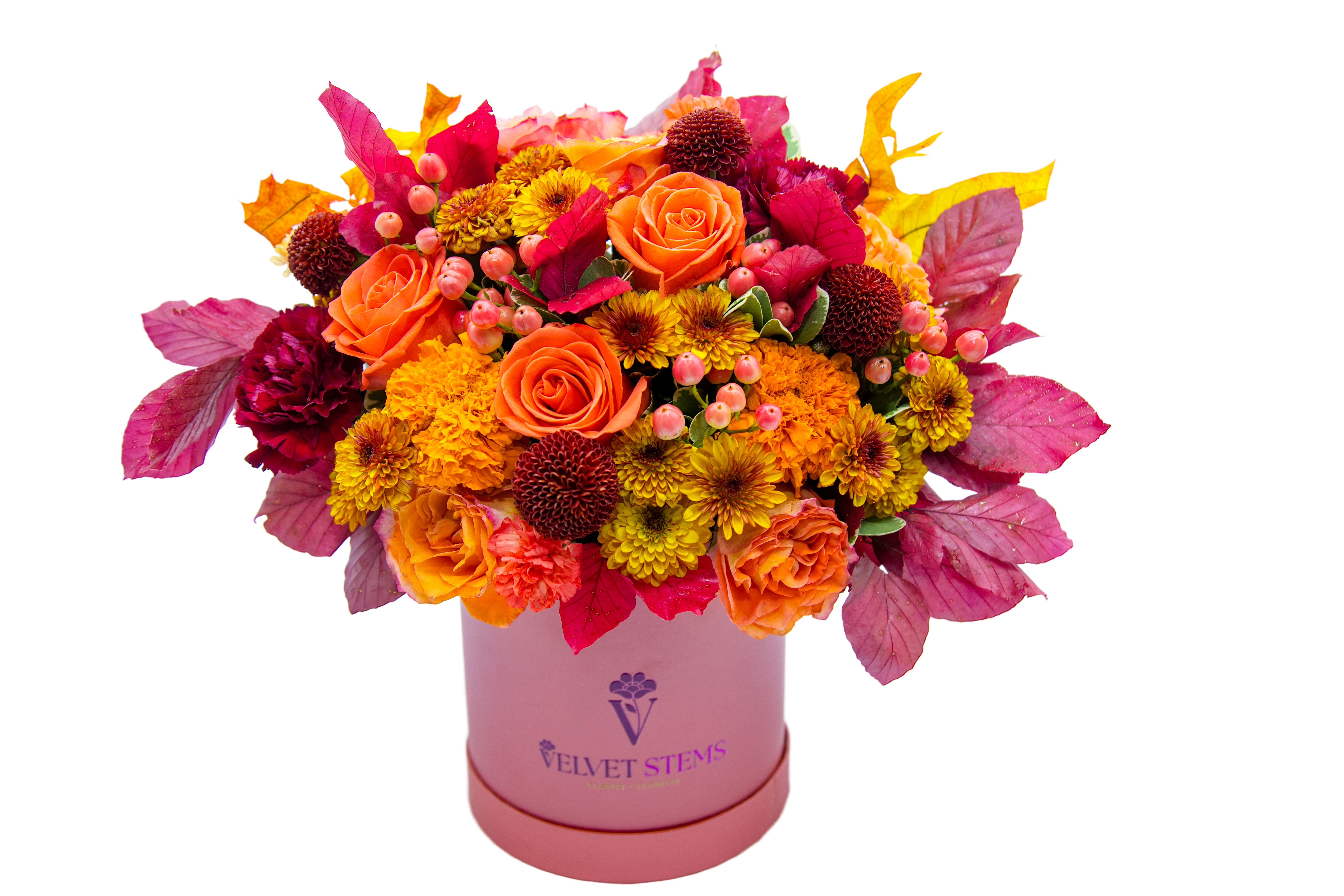 Orange and yellow mixed bouquet in a pink hatbox with magenta foliage
