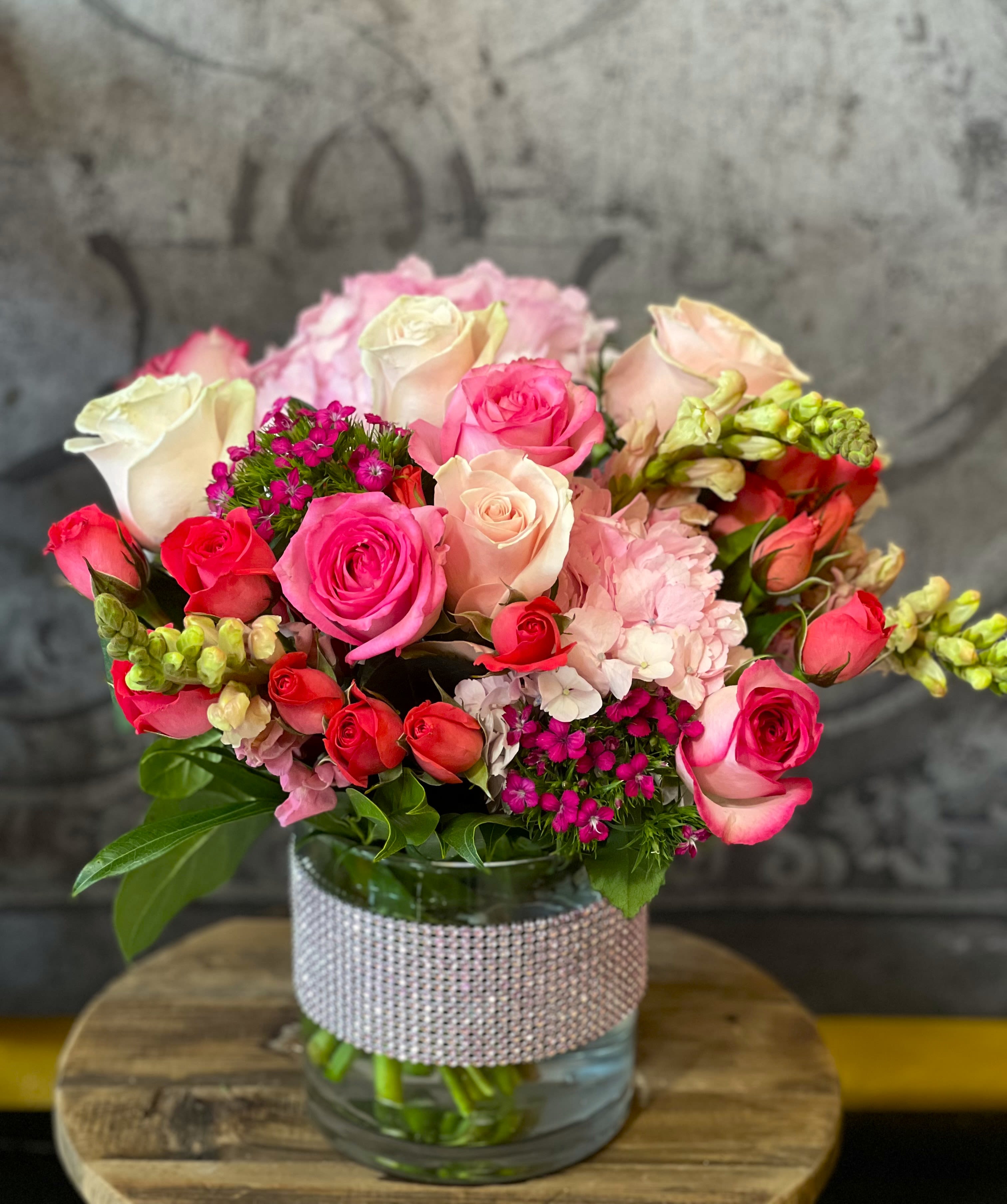 Bouquet of pink and white roses in a glass vase with a rhinestone wrap