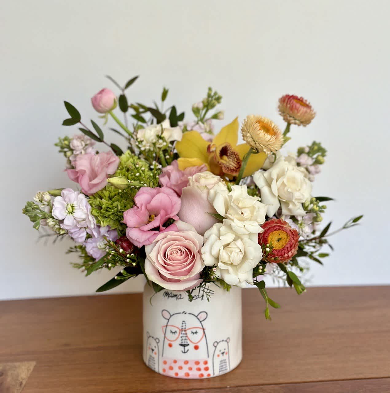 Mixed bouquet of pink, white, and yellow flowers in a decorated ceramic vase