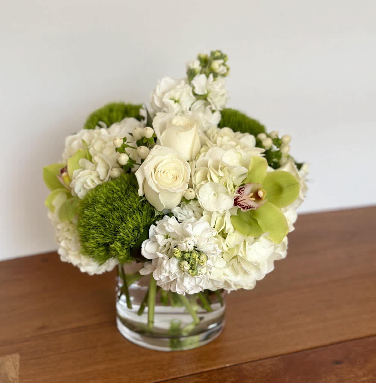 White floral arrangement in a clear glass vase with bright green accents