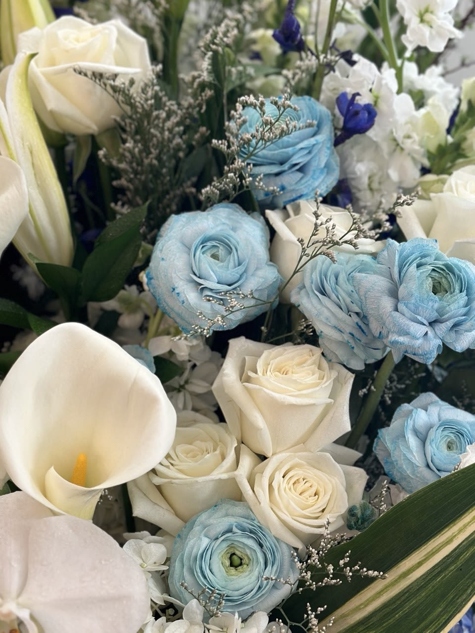 Bouquet of white roses, blue ranunculus, and white calla lilies