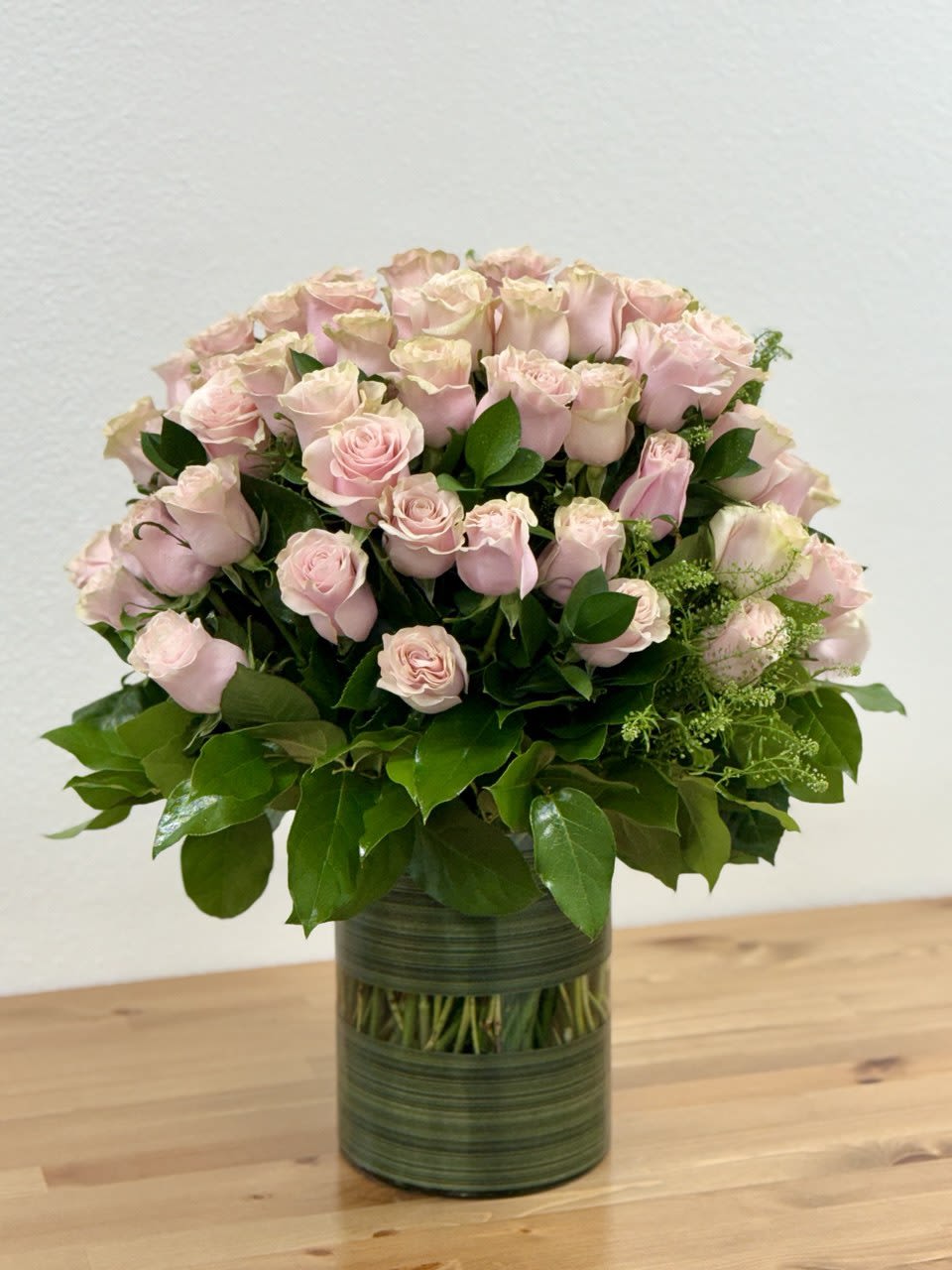 Pink roses arranged in a green glass vase