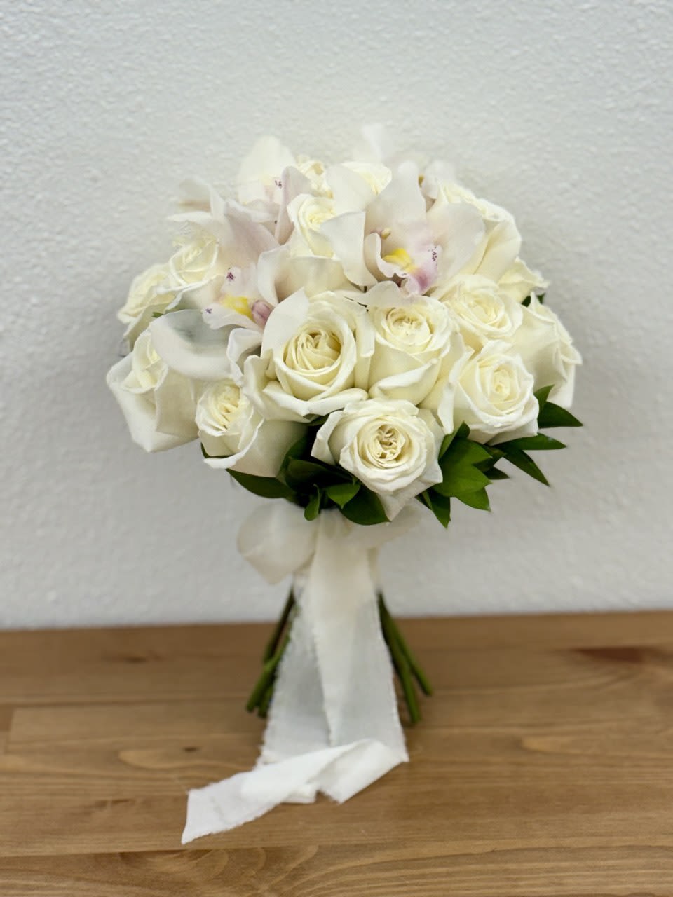 White rose and orchid bouquet with a white ribbon wrap