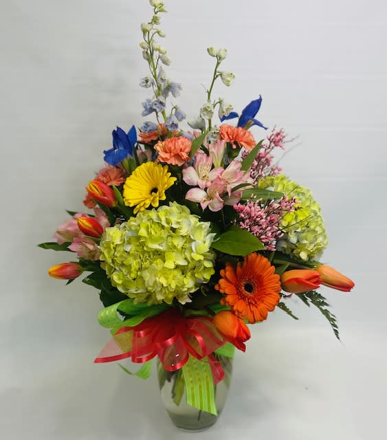 Colorful mixed flower bouquet in a glass vase with ribbon