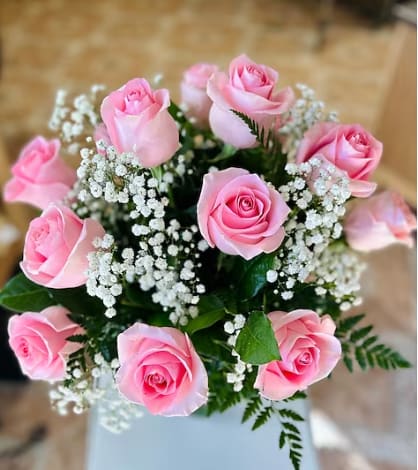 Pink roses arranged with white baby's breath in a vase
