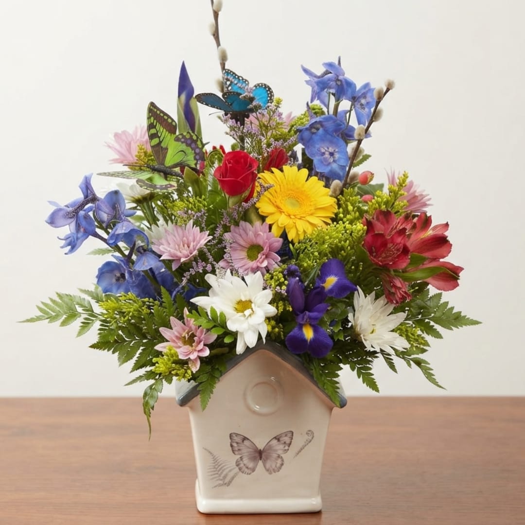 Colorful mixed flower arrangement in a butterfly-decorated ceramic house vase