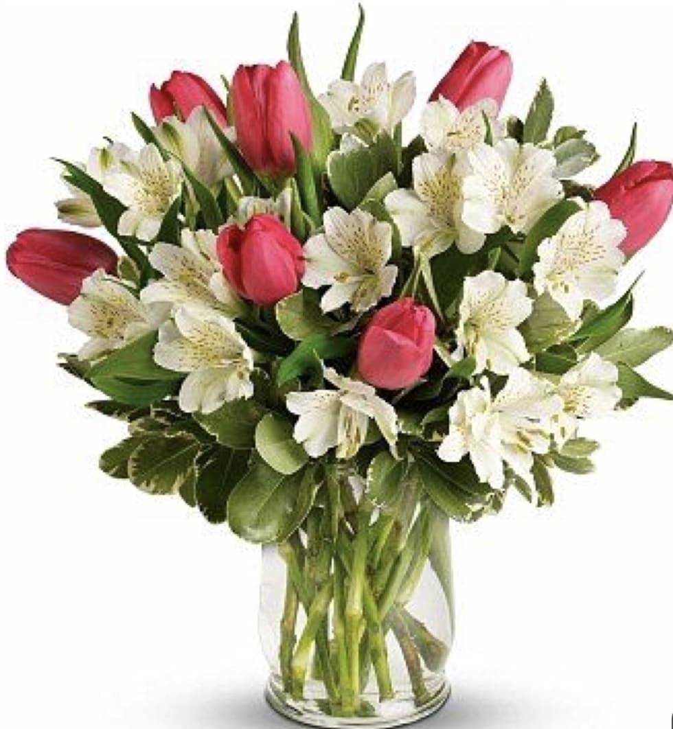 Pink tulips and white flowers arranged in a clear glass vase
