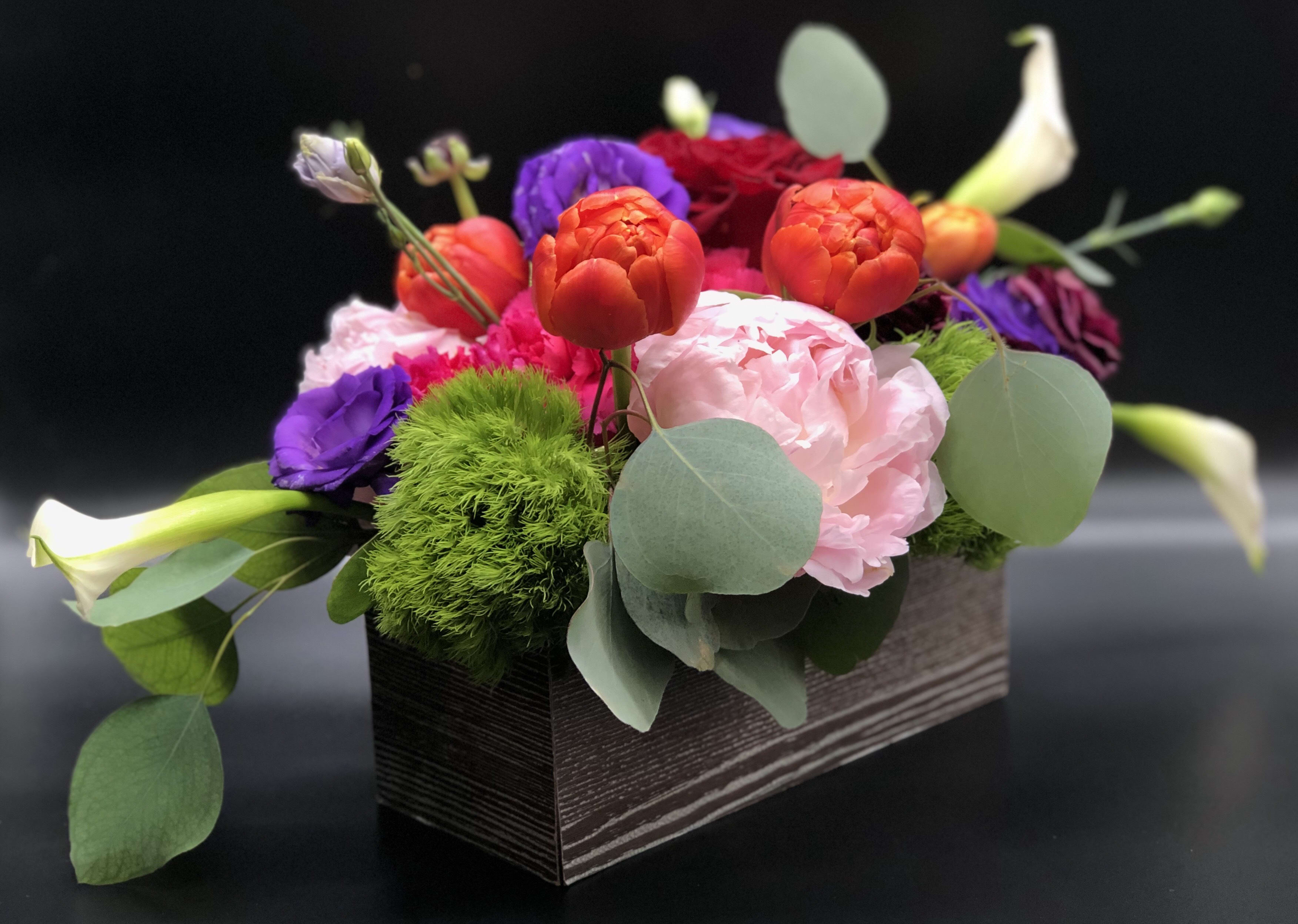 Colorful mixed flower arrangement in a rectangular box with calla lilies