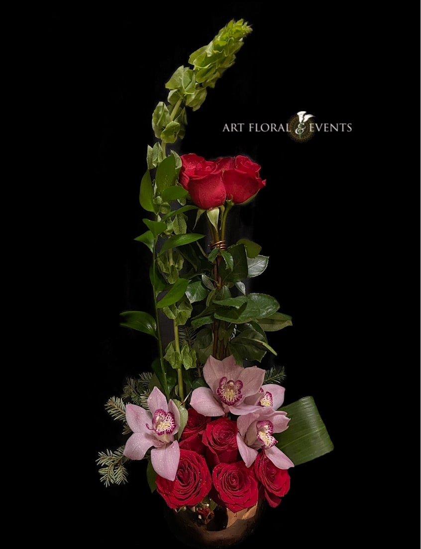Tall floral arrangement with red roses and pink orchids in a vase