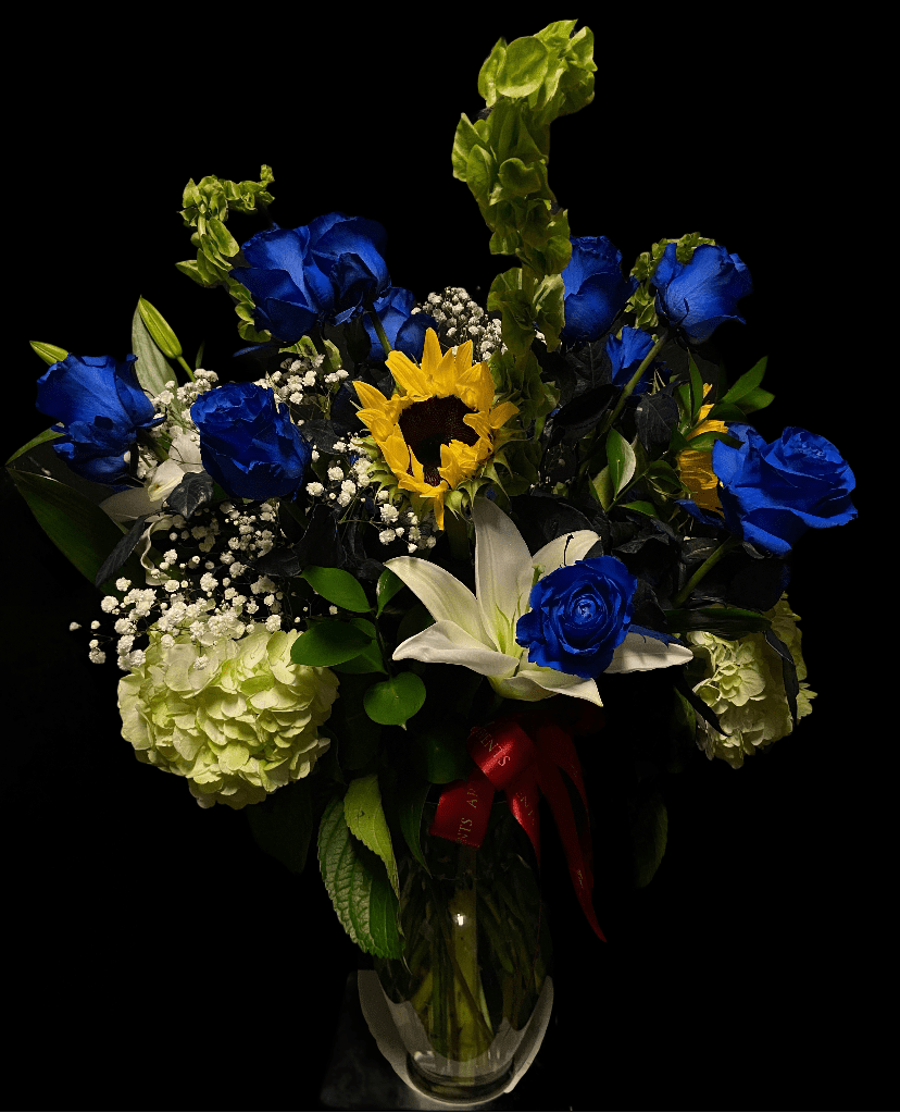 Blue roses and a sunflower in a glass vase