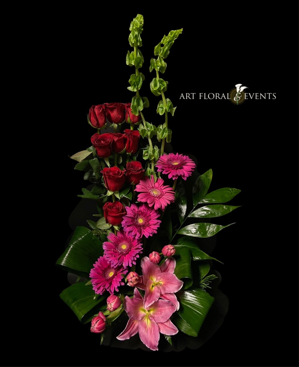 Tall floral arrangement with red roses, pink gerbera daisies, and pink lilies