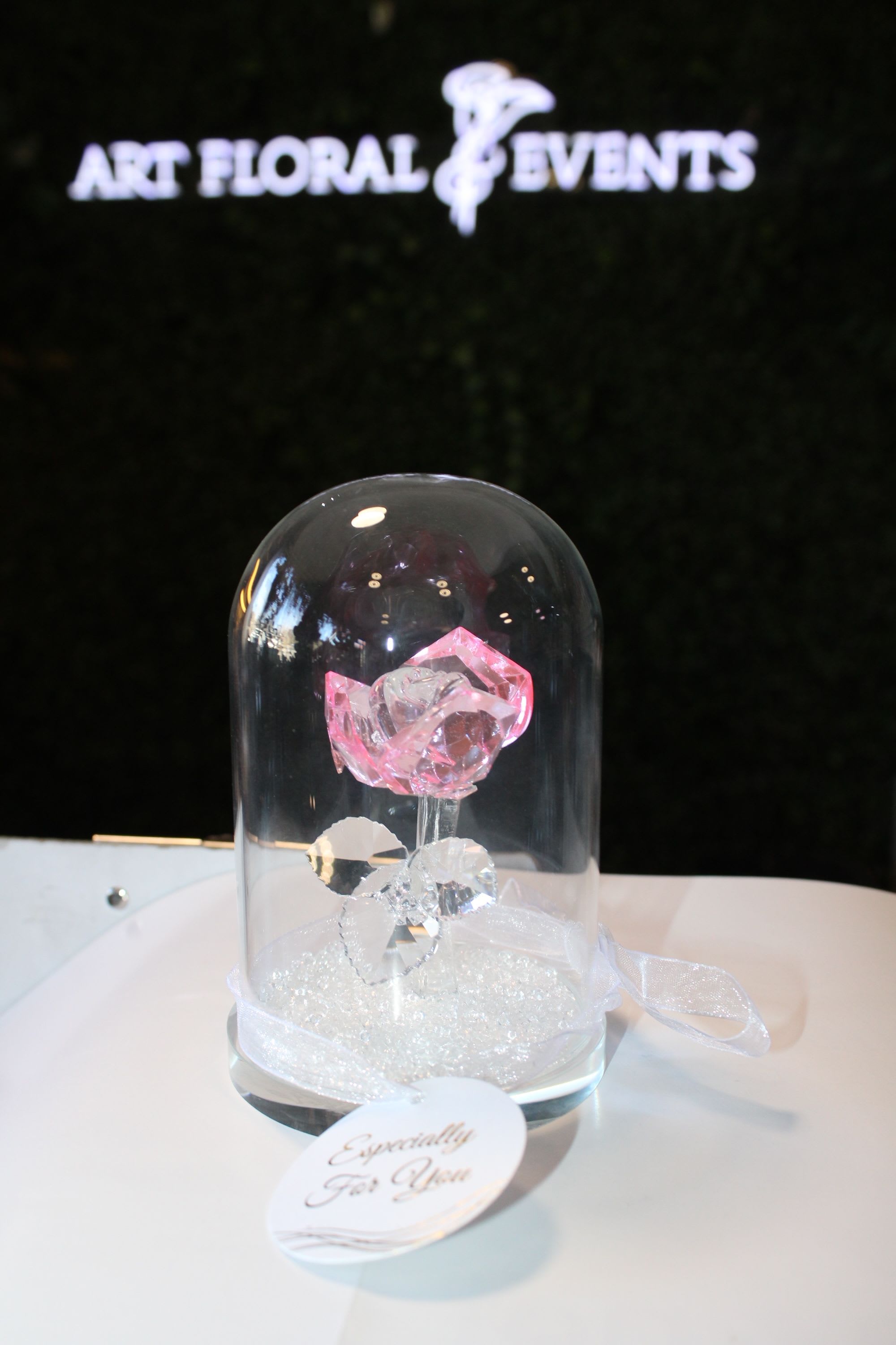 Pink crystal rose under a glass dome with a ribbon base
