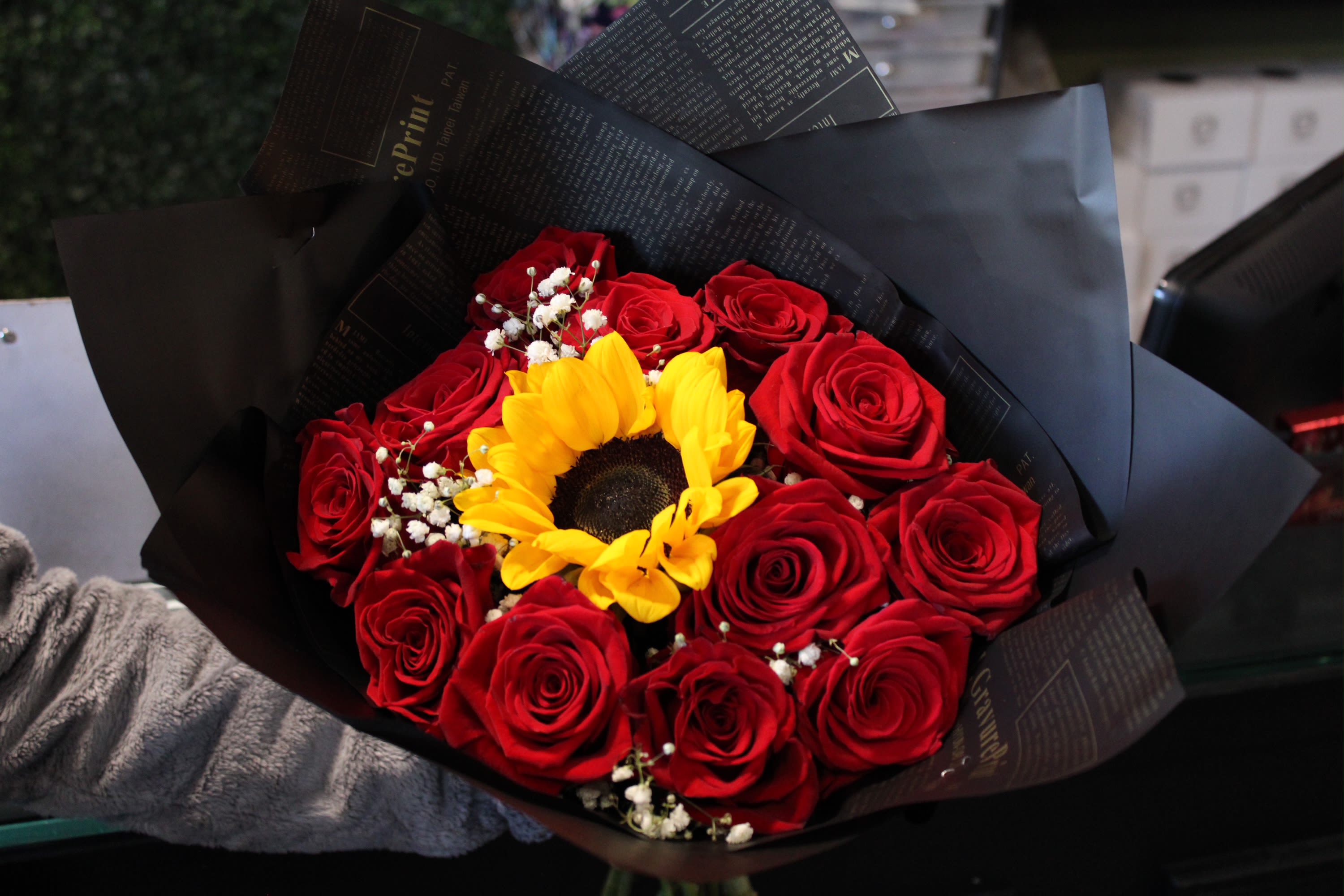 Bouquet of red roses with a yellow sunflower in black wrapping