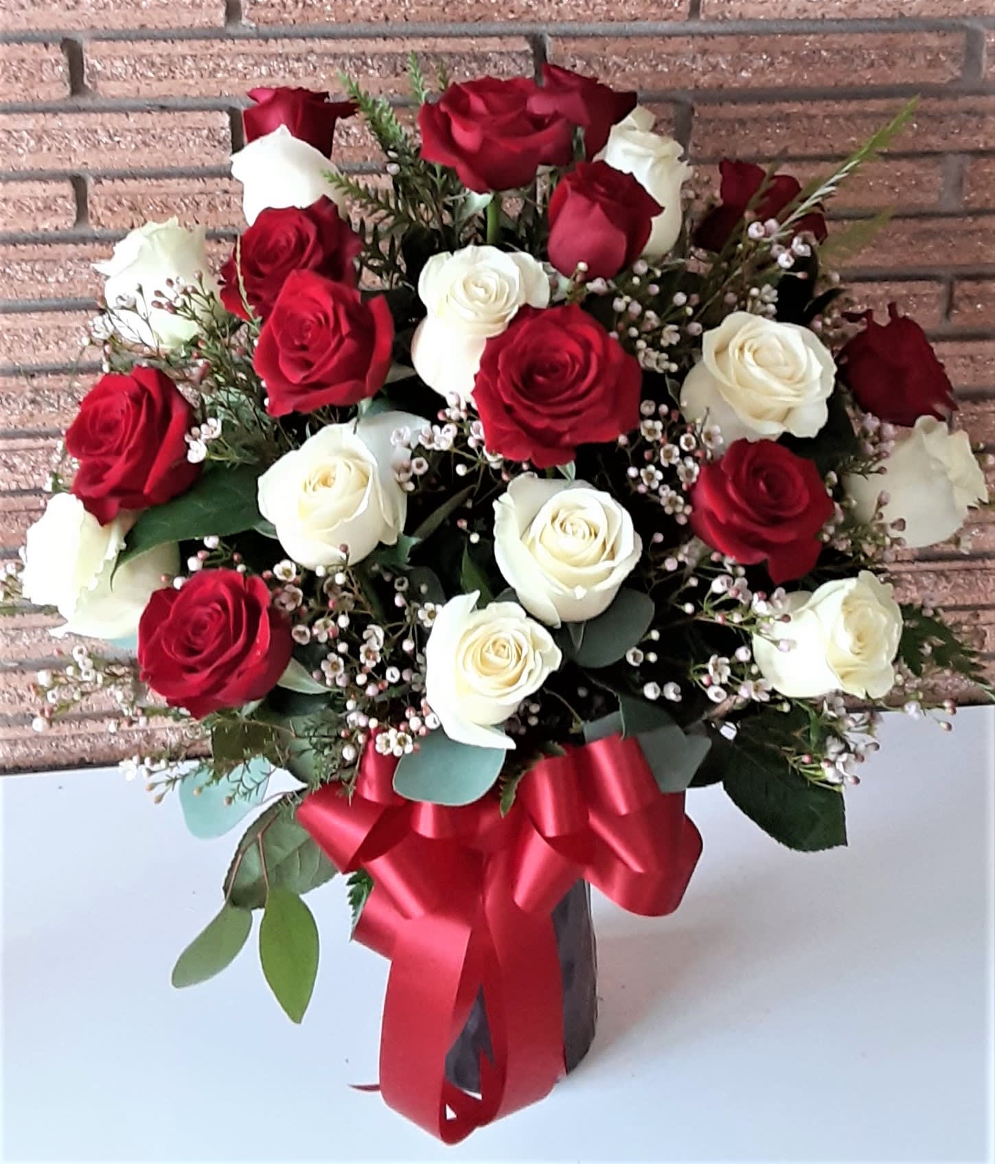 Bouquet of red and white roses with a red ribbon in a vase