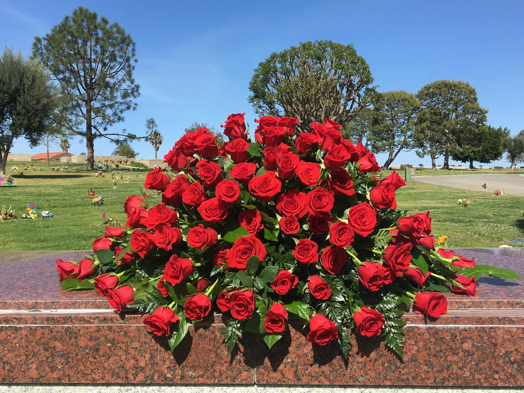 Large bouquet of red roses arranged on a stone memorial ledge
