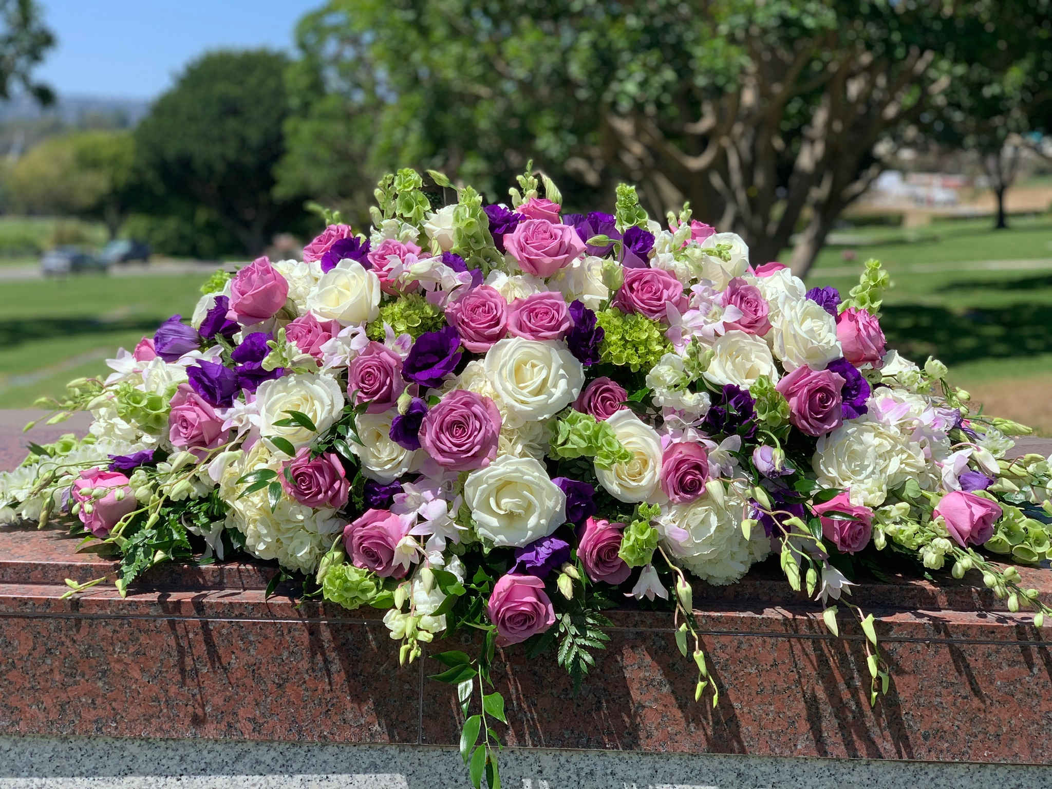 Large arrangement of pink, white, and purple roses on a stone ledge