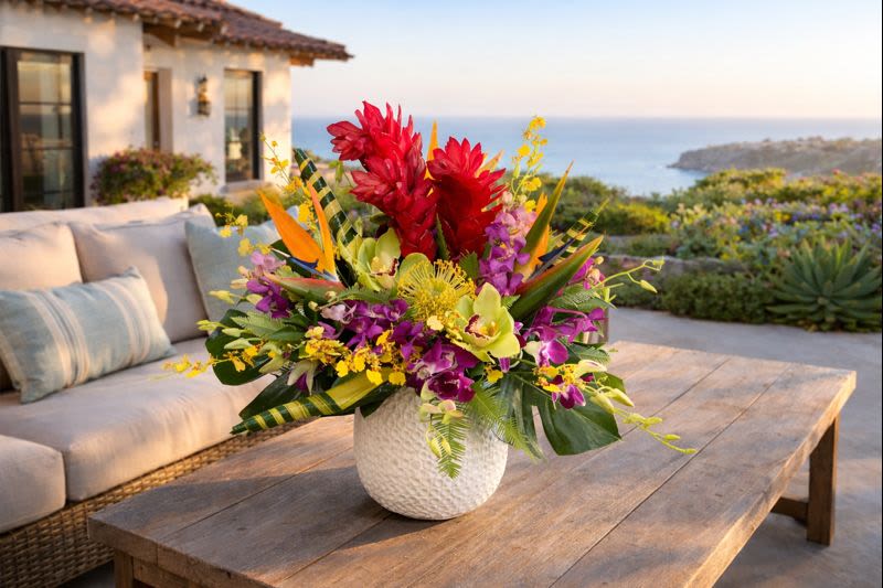 Tropical flower arrangement in a white textured vase on a wooden table