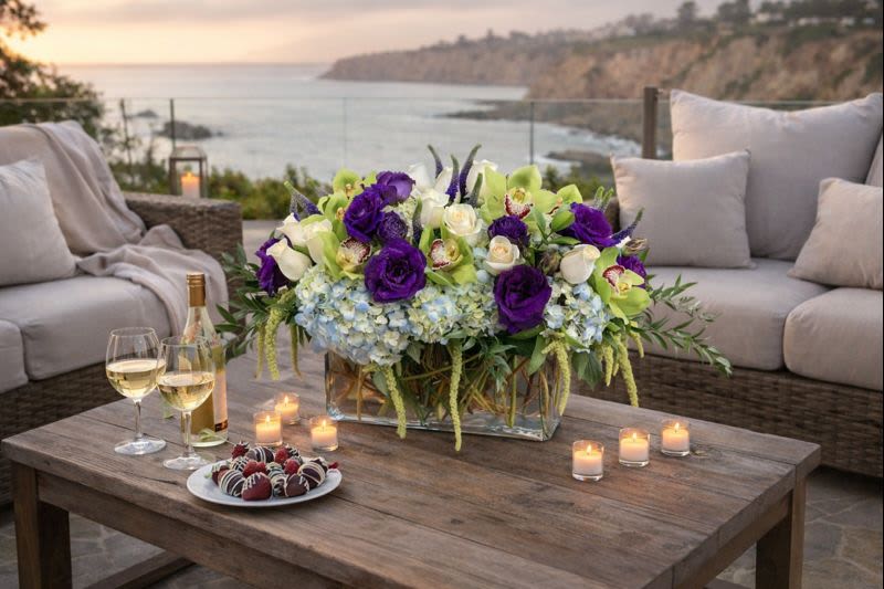 Purple and white floral centerpiece on a table with candles and wine glasses