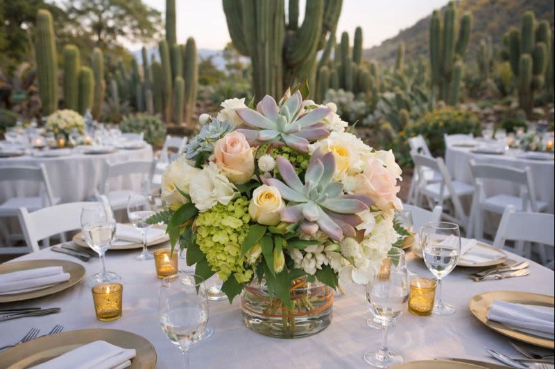 Low floral centerpiece in a glass vase on a set table outdoors