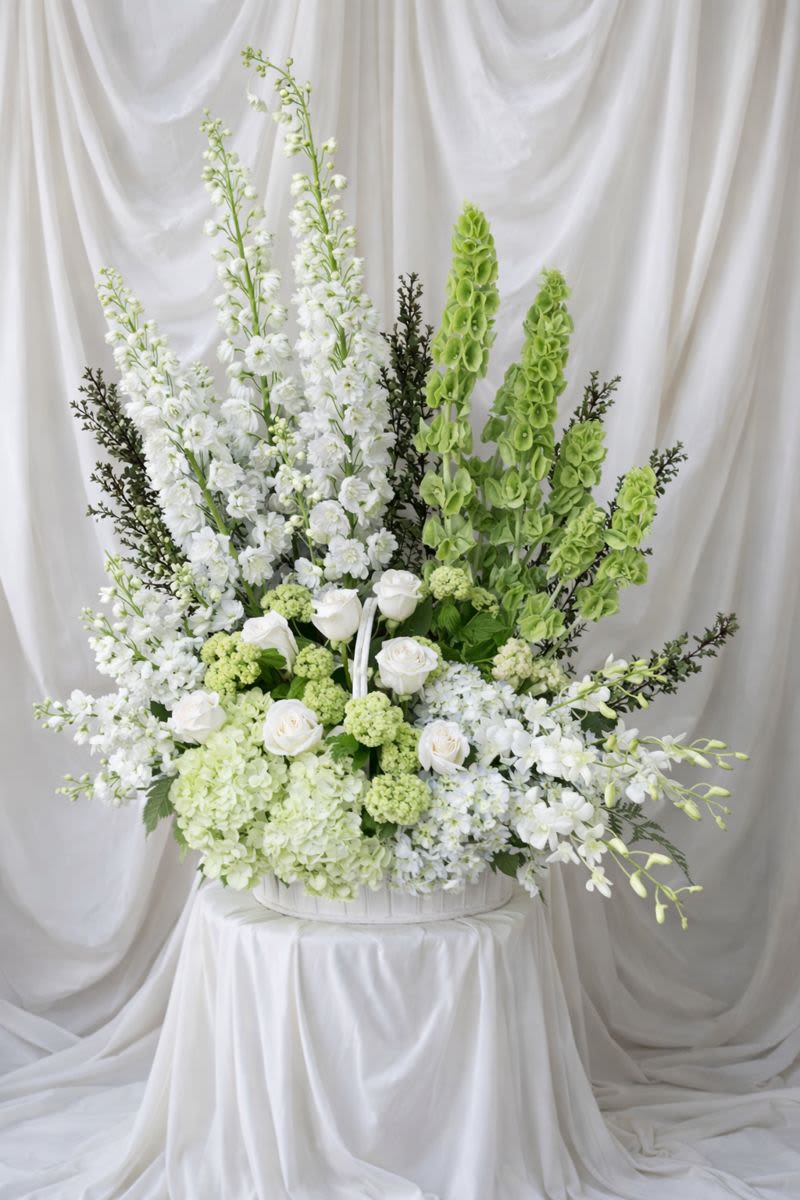 Large white and green floral arrangement in a white container