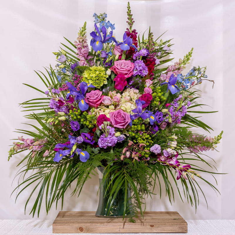 Large mixed bouquet of purple, pink, and blue flowers in a glass vase